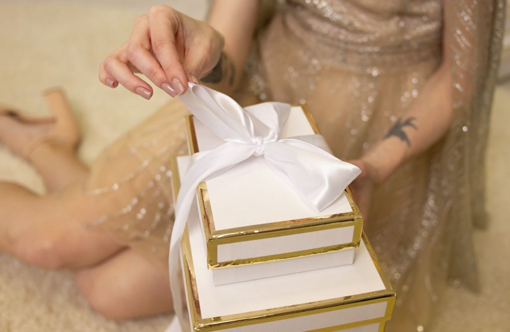 Close-up of a woman tying a bow on a white gift box, perfect for festive occasions.