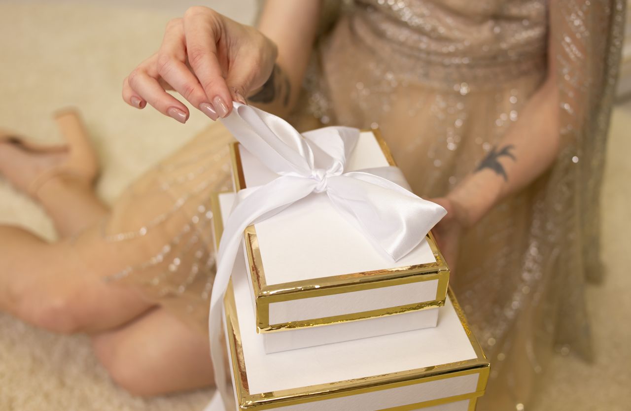 Services Close-up of a woman tying a bow on a white gift box, perfect for festive occasions.