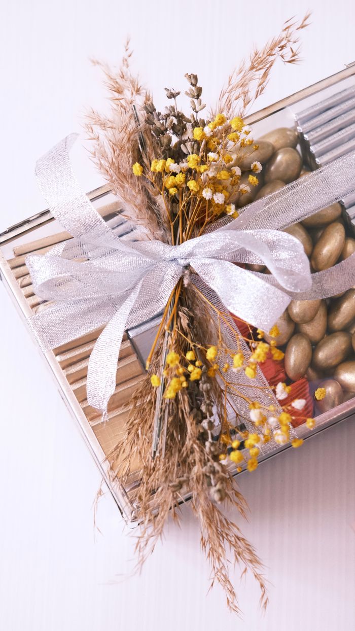 Stylish gift box adorned with a silver bow and dried flowers, perfect for celebrations.