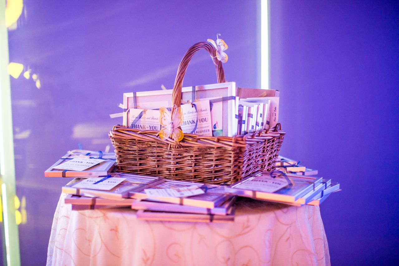 Services A beautifully arranged gift basket on a round table, illuminated by purple lighting for an elegant event setup.