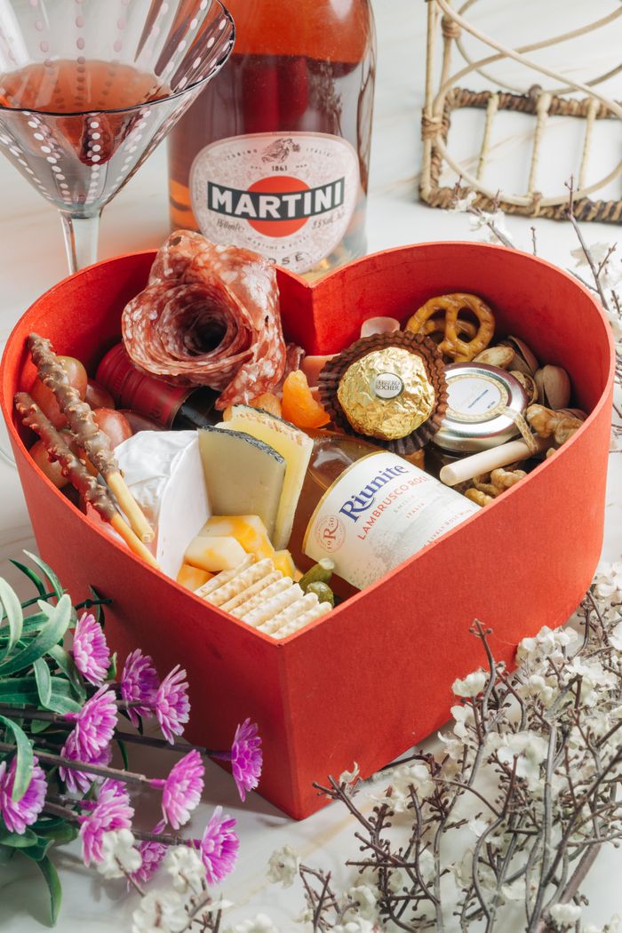 Elegant heart-shaped gift box with gourmet food items and wine, perfect for special occasions or gifts.